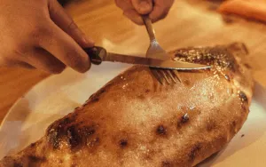 Calzone Dolce being cut with a knife and fork to share.